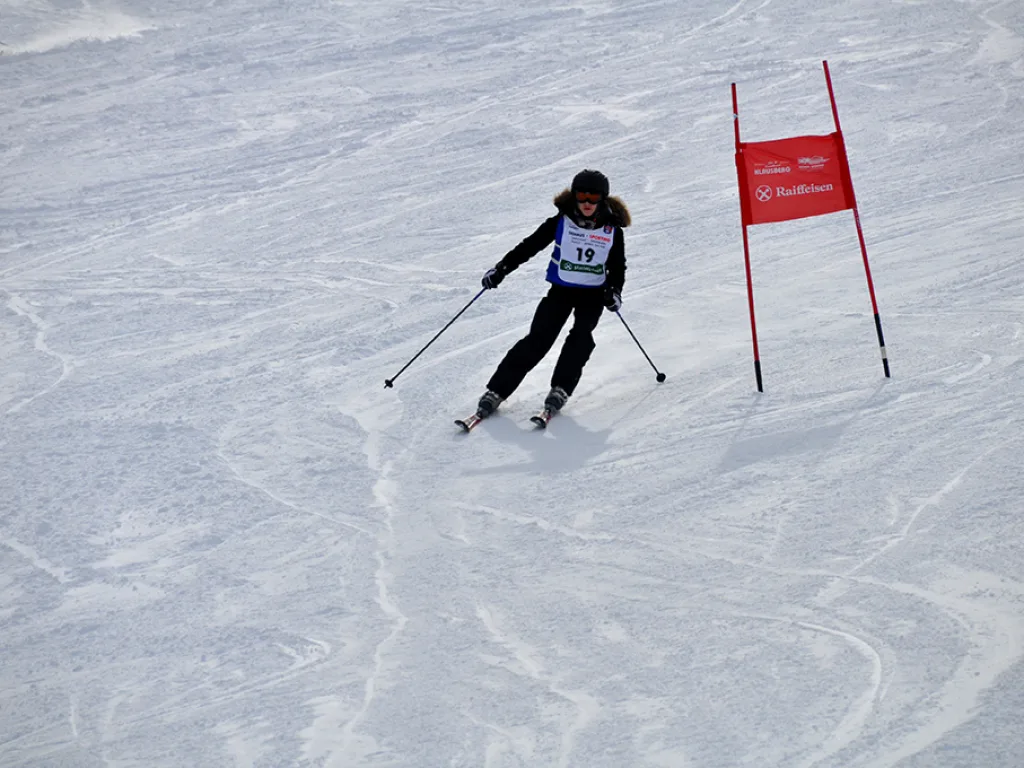Skifahrerin in der Kurve neben einem roten Tor.